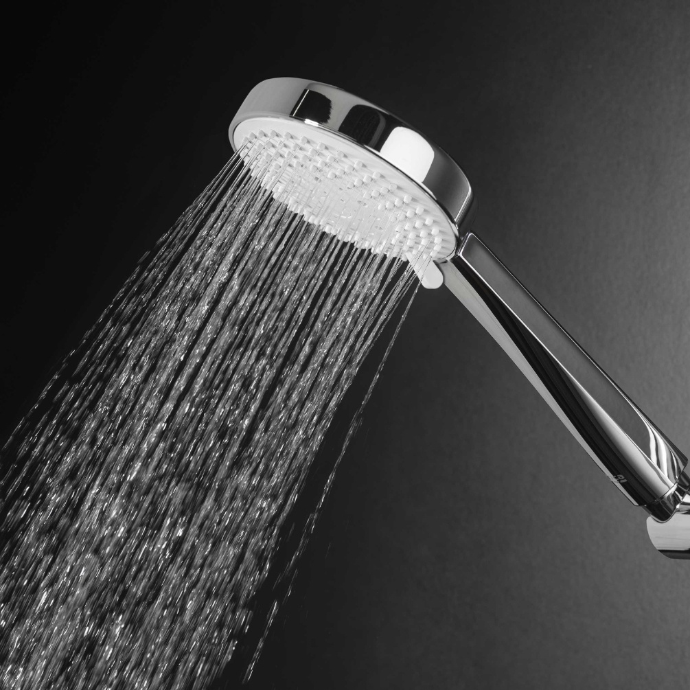 Lifestyle image of the Roca Sensum Chrome 3 Function Round Handset Shower spraying water